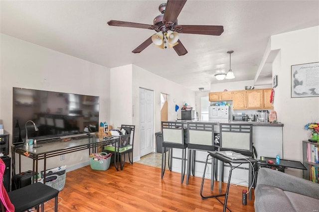 interior space with ceiling fan, light brown cabinets, white refrigerator, decorative light fixtures, and light wood-type flooring