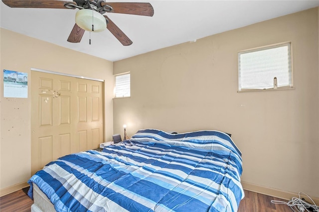 bedroom with dark hardwood / wood-style floors, a closet, and ceiling fan