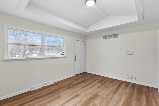 empty room featuring a tray ceiling and wood-type flooring