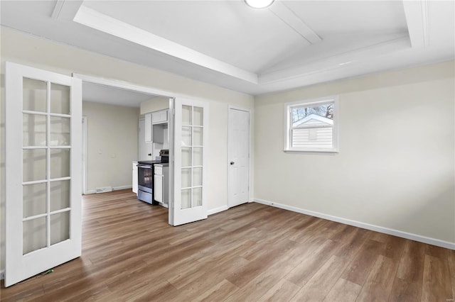 spare room featuring french doors, a raised ceiling, and hardwood / wood-style floors