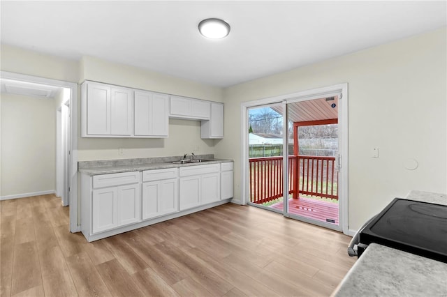 kitchen with range, light wood-type flooring, white cabinetry, and sink