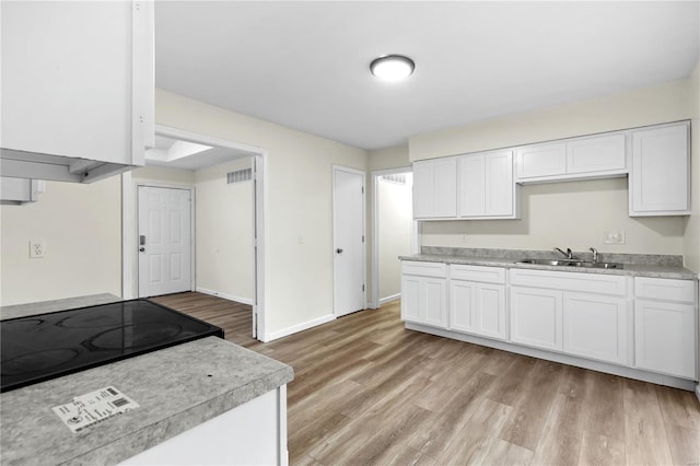 kitchen featuring white cabinetry, sink, and light wood-type flooring