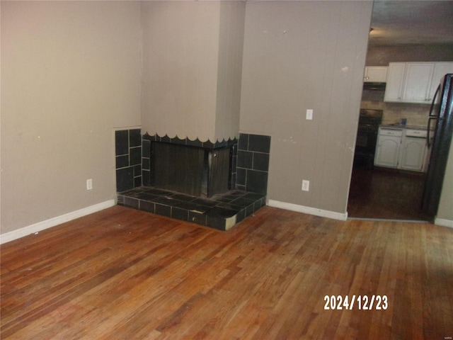 unfurnished living room with a tile fireplace and wood-type flooring