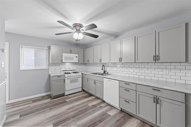 kitchen featuring sink, gray cabinetry, white appliances, and decorative backsplash