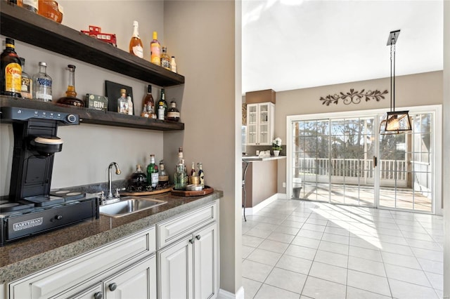 bar featuring white cabinetry, sink, light tile patterned floors, and decorative light fixtures