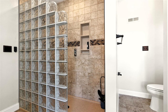 bathroom with a tile shower and toilet