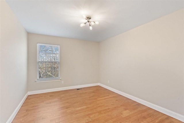 empty room featuring light hardwood / wood-style floors and a notable chandelier