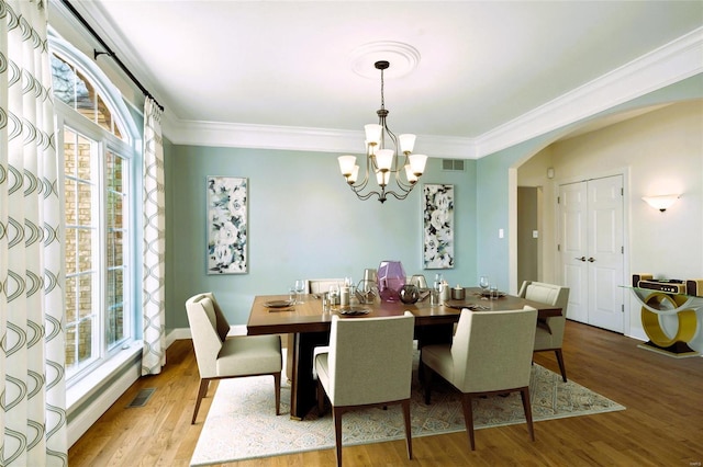 dining area featuring light hardwood / wood-style floors, crown molding, a wealth of natural light, and a chandelier