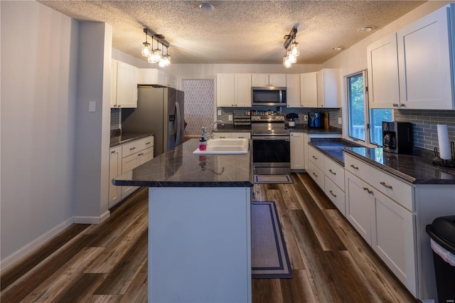 kitchen featuring a kitchen island, white cabinetry, sink, and appliances with stainless steel finishes