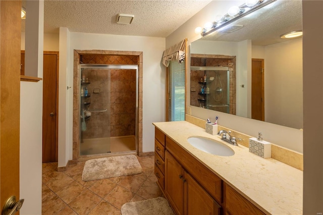 bathroom featuring a textured ceiling, vanity, tile patterned floors, and an enclosed shower