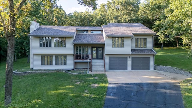 raised ranch featuring a garage and a front lawn