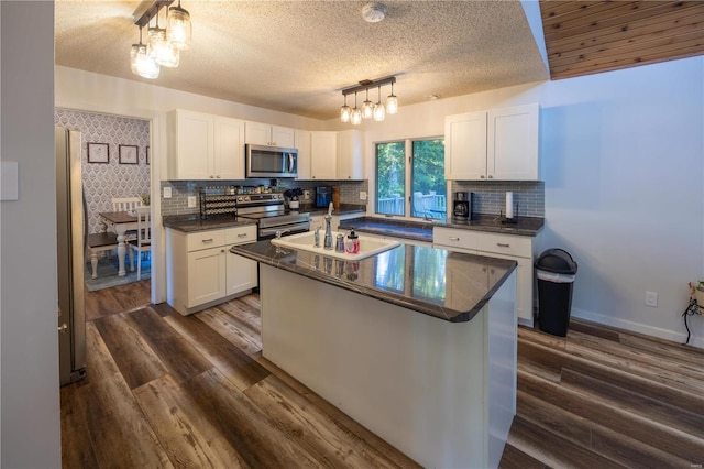 kitchen with stainless steel appliances, dark hardwood / wood-style flooring, an island with sink, and white cabinets