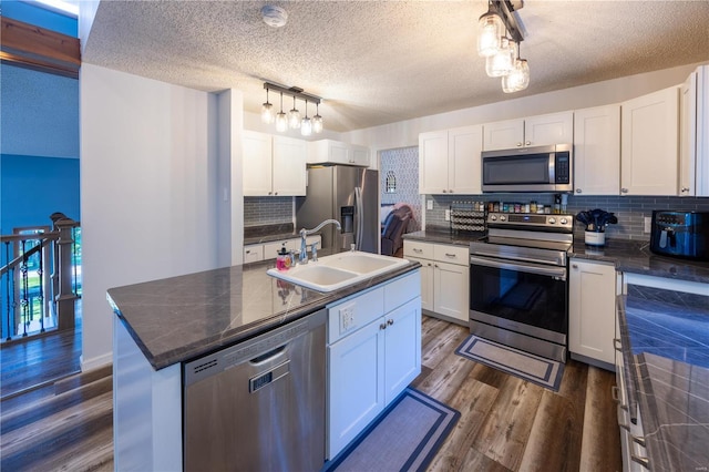 kitchen with sink, stainless steel appliances, dark hardwood / wood-style floors, an island with sink, and white cabinets