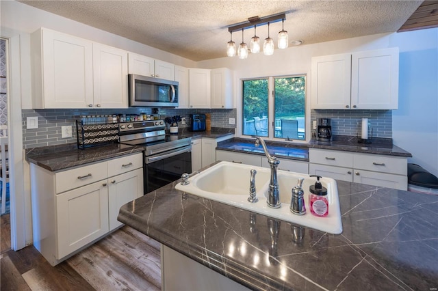 kitchen with stainless steel appliances, hanging light fixtures, and white cabinets