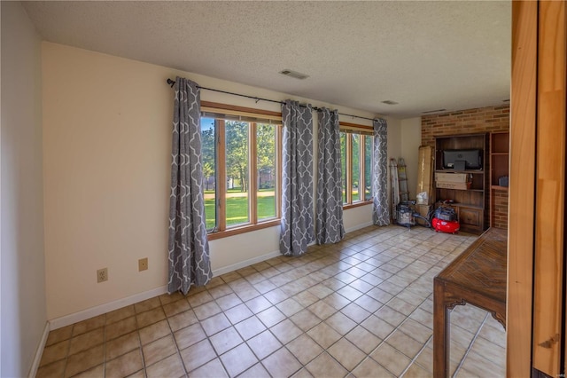 spare room featuring light tile patterned floors and a textured ceiling