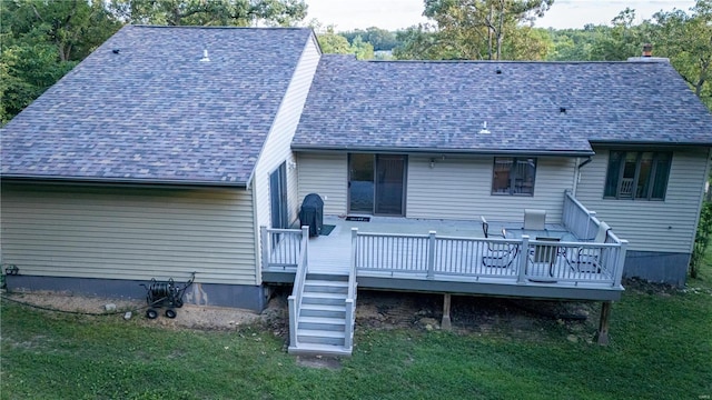 rear view of house with a wooden deck and a lawn