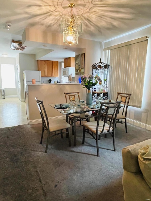 carpeted dining area with an inviting chandelier