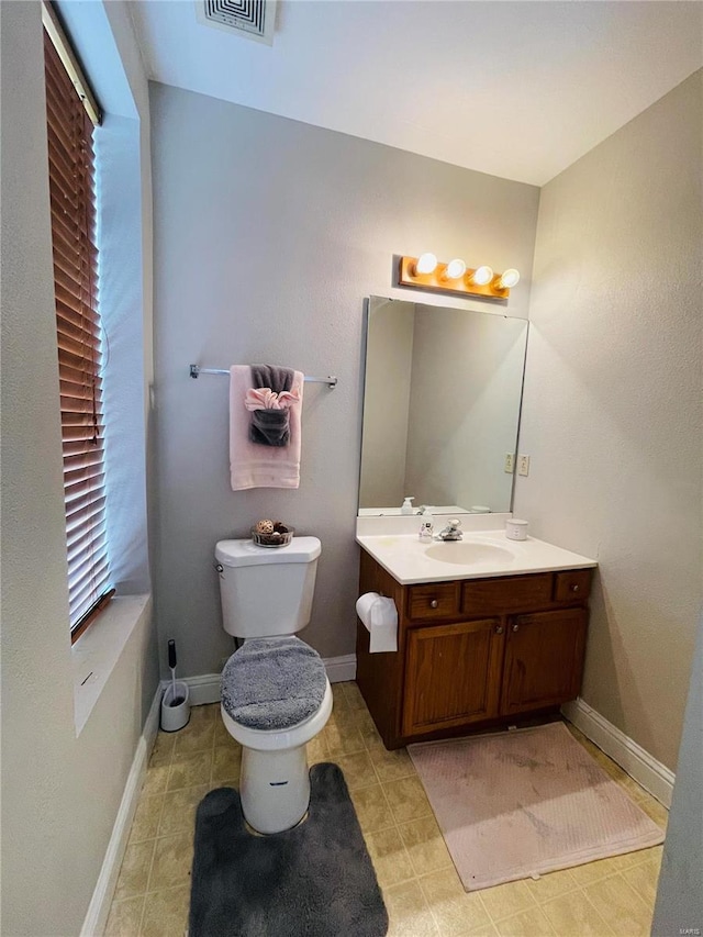 bathroom featuring a wealth of natural light, vanity, and toilet