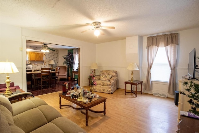 living room featuring a textured ceiling, light hardwood / wood-style floors, and ceiling fan