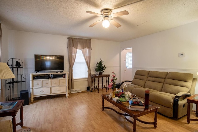 living room featuring ceiling fan, a textured ceiling, and light hardwood / wood-style flooring