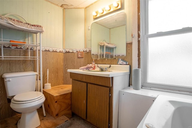 bathroom featuring wood walls, vanity, and toilet