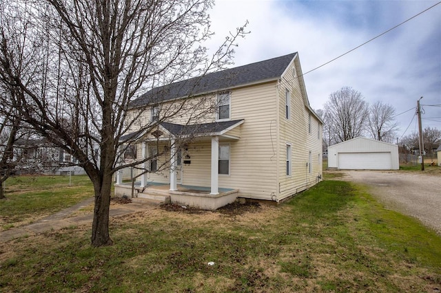 view of front of property featuring a porch, a garage, an outbuilding, and a front lawn