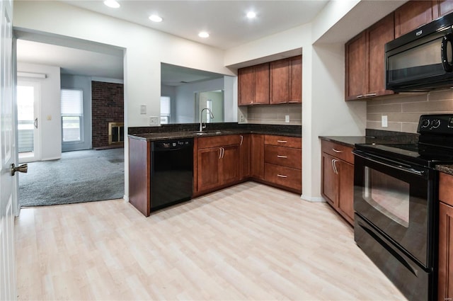 kitchen featuring sink, dark stone countertops, light colored carpet, decorative backsplash, and black appliances