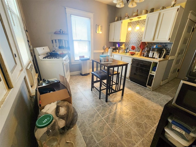 kitchen with decorative backsplash, dishwasher, white cabinets, and white range with gas stovetop