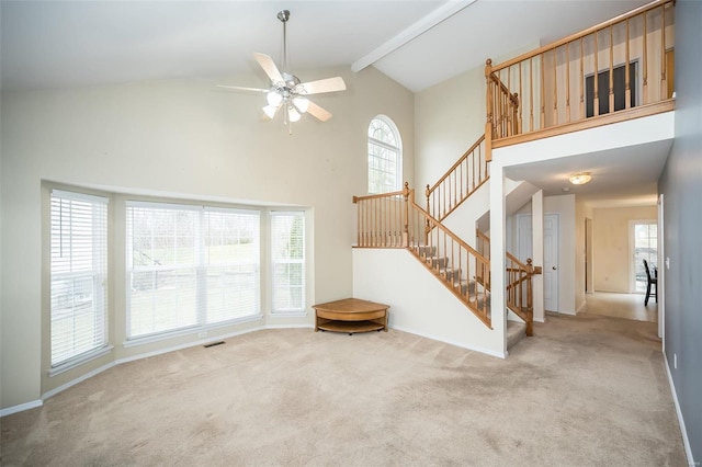 unfurnished living room with beam ceiling, light carpet, high vaulted ceiling, and ceiling fan