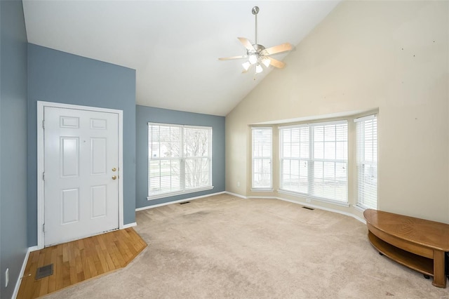 entryway with ceiling fan, light colored carpet, and high vaulted ceiling