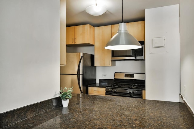 kitchen with appliances with stainless steel finishes, light brown cabinets, dark stone counters, and pendant lighting