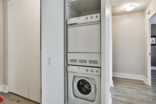 laundry room featuring stacked washer / drying machine and light wood-type flooring