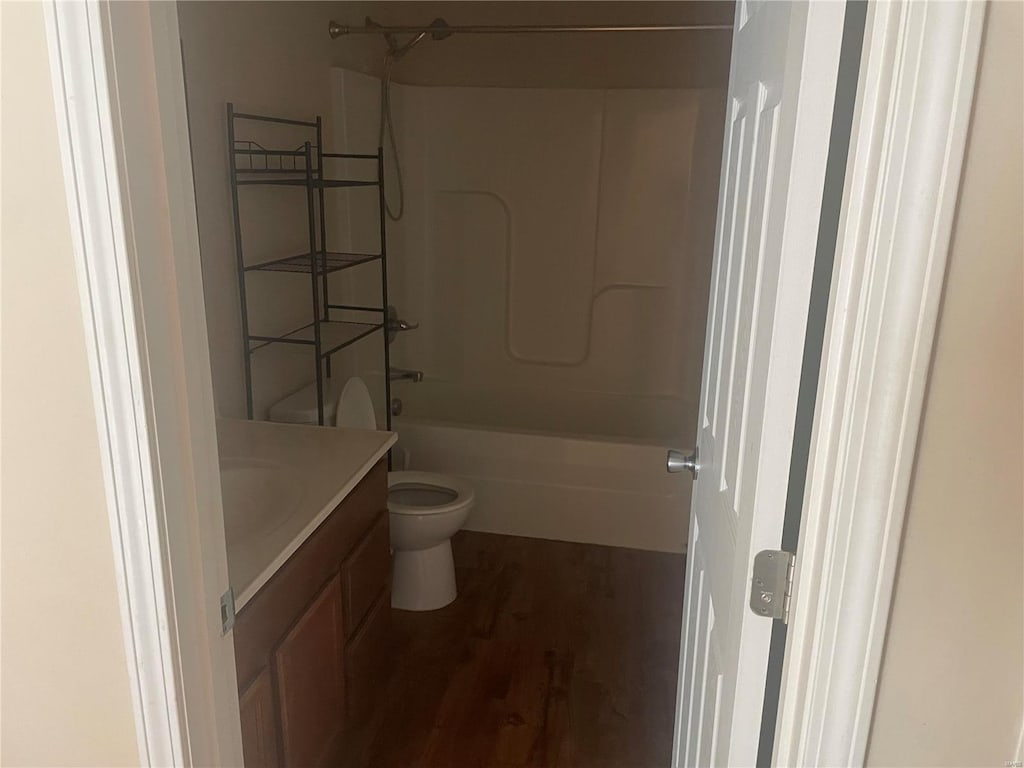 full bathroom with hardwood / wood-style flooring, shower / bathtub combination, vanity, and toilet