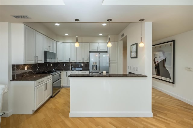 kitchen with double oven range, pendant lighting, white cabinets, and refrigerator with ice dispenser