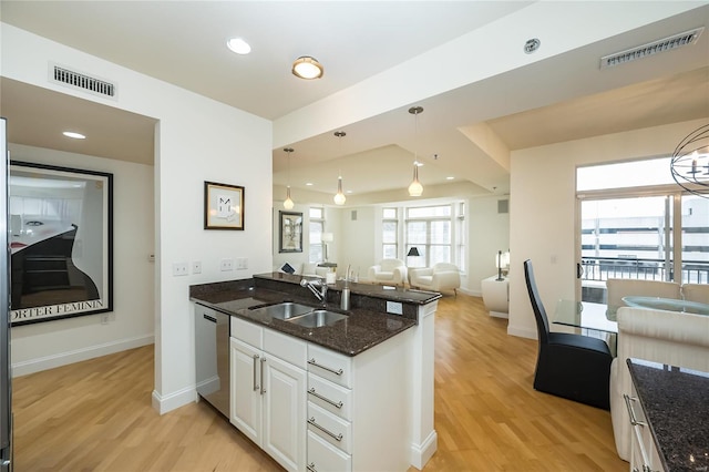 kitchen with white cabinetry, dark stone countertops, dishwasher, hanging light fixtures, and sink