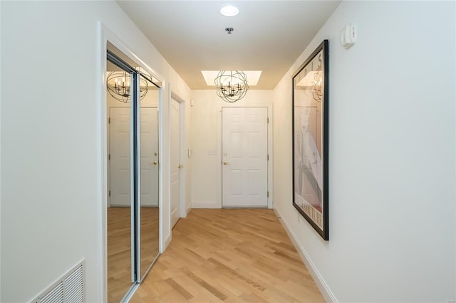 hallway featuring light wood-type flooring and a chandelier