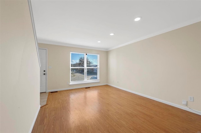 empty room with light hardwood / wood-style floors and ornamental molding