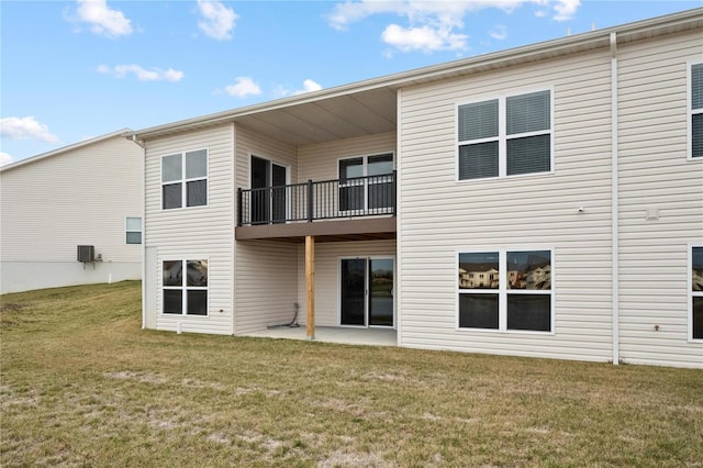 back of property with central AC unit, a balcony, a yard, and a patio