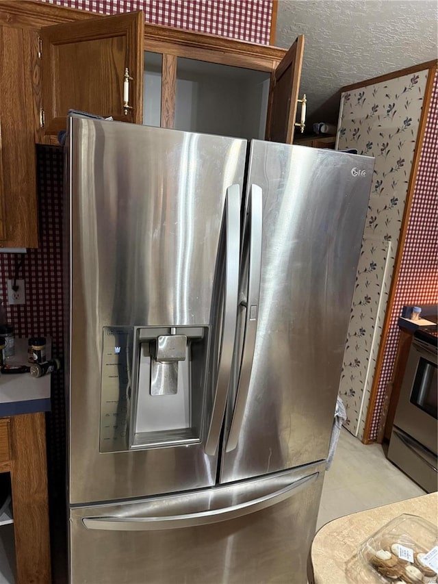 kitchen featuring stainless steel fridge, a textured ceiling, and stove