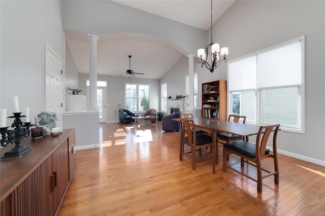 dining room featuring ornate columns, ceiling fan, high vaulted ceiling, and light wood-type flooring