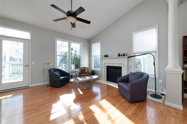 living room featuring ornate columns, a wealth of natural light, and light hardwood / wood-style flooring