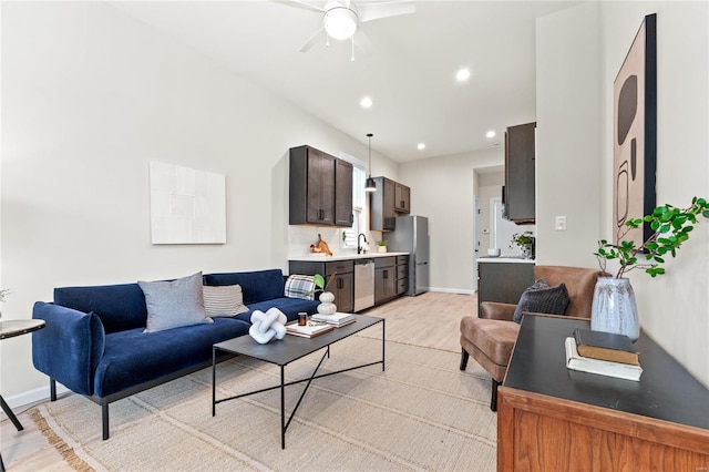 living room with ceiling fan, sink, and light wood-type flooring