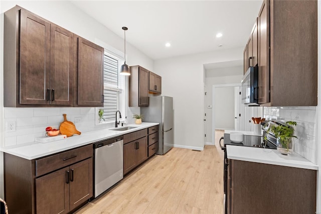 kitchen featuring sink, stainless steel appliances, tasteful backsplash, pendant lighting, and dark brown cabinets