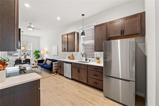 kitchen with ceiling fan, sink, stainless steel appliances, decorative light fixtures, and dark brown cabinets