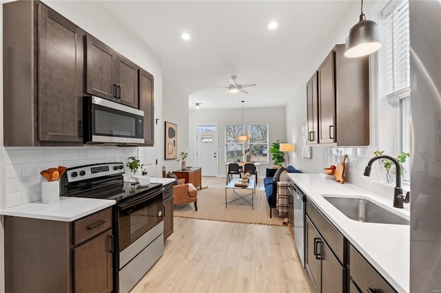 kitchen featuring pendant lighting, dark brown cabinetry, sink, and stainless steel appliances