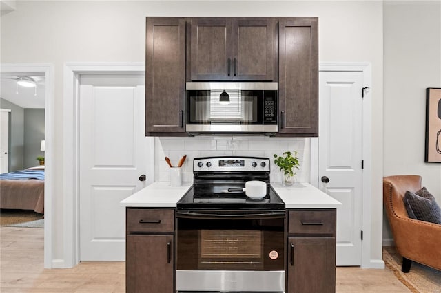 kitchen featuring dark brown cabinets, backsplash, appliances with stainless steel finishes, and light hardwood / wood-style flooring