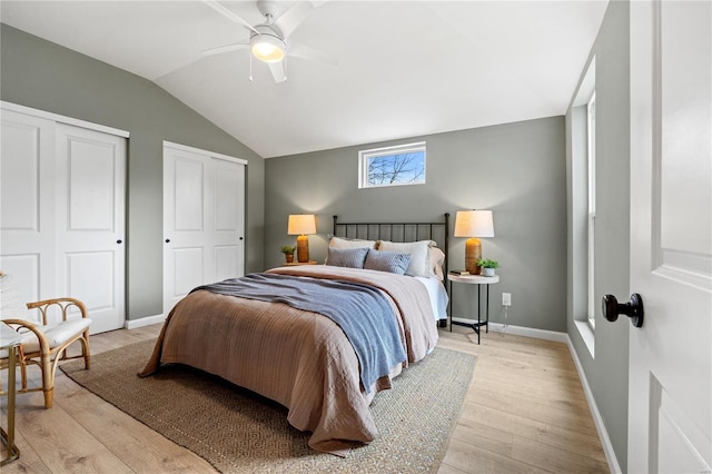 bedroom featuring ceiling fan, light hardwood / wood-style flooring, and two closets