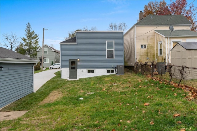 rear view of property featuring a lawn and central air condition unit