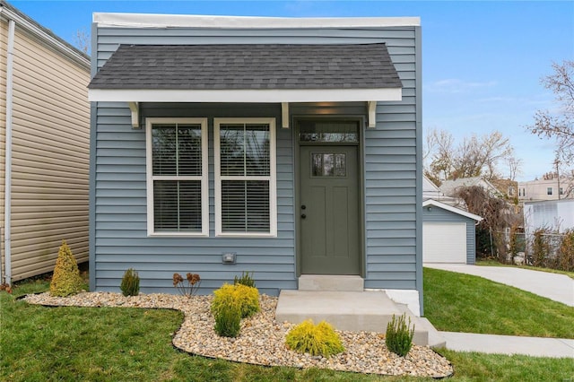 doorway to property featuring a detached garage and a shingled roof