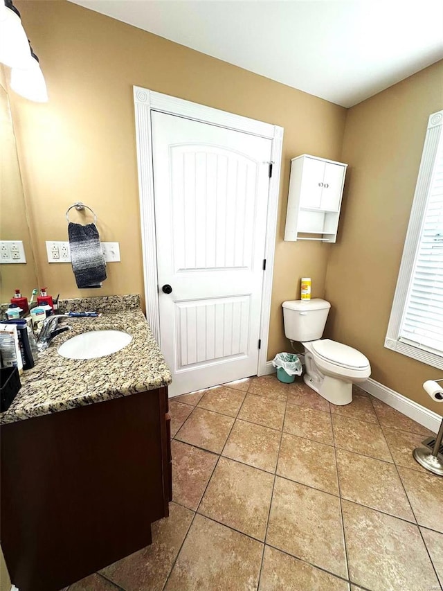 bathroom with toilet, vanity, and tile patterned floors